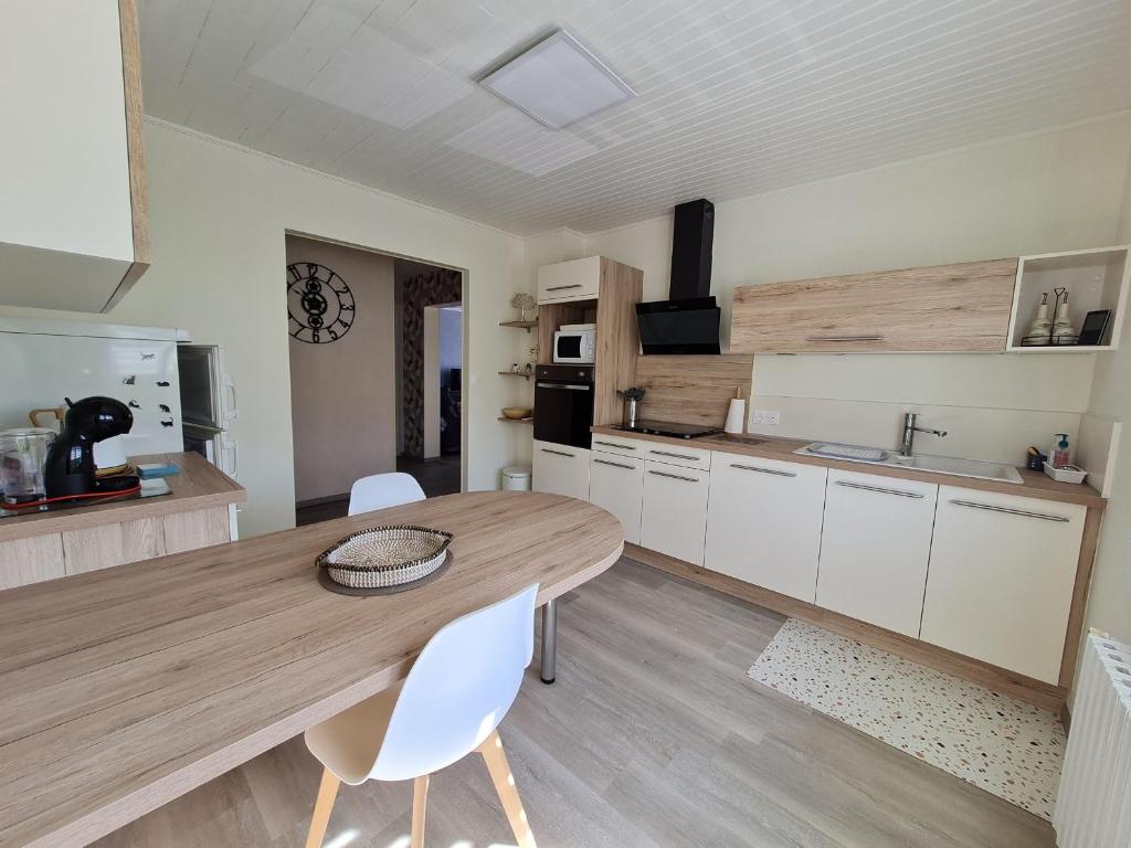 a kitchen with a wooden table and white chairs at Gîte Vilosnes-Haraumont, 4 pièces, 5 personnes - FR-1-585-82 