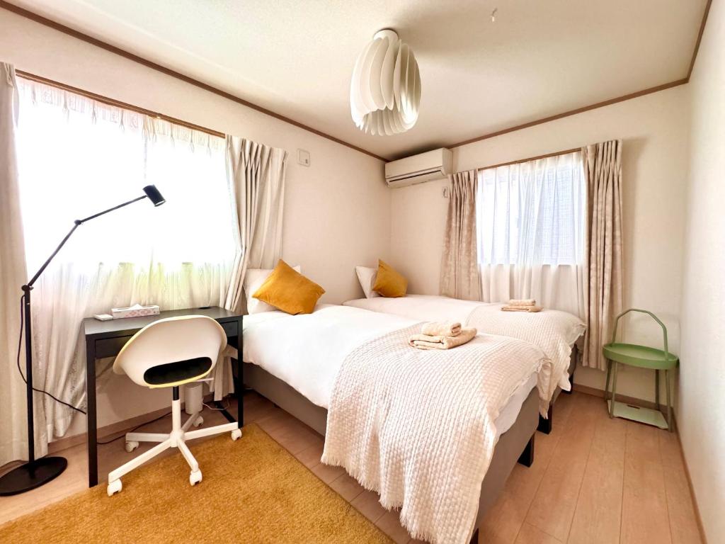 a bedroom with two beds and a desk and a window at KANAU in Tokyo