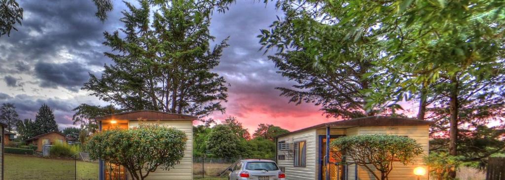 un coche aparcado delante de una casa pequeña en Highlander Van Village, en Armidale