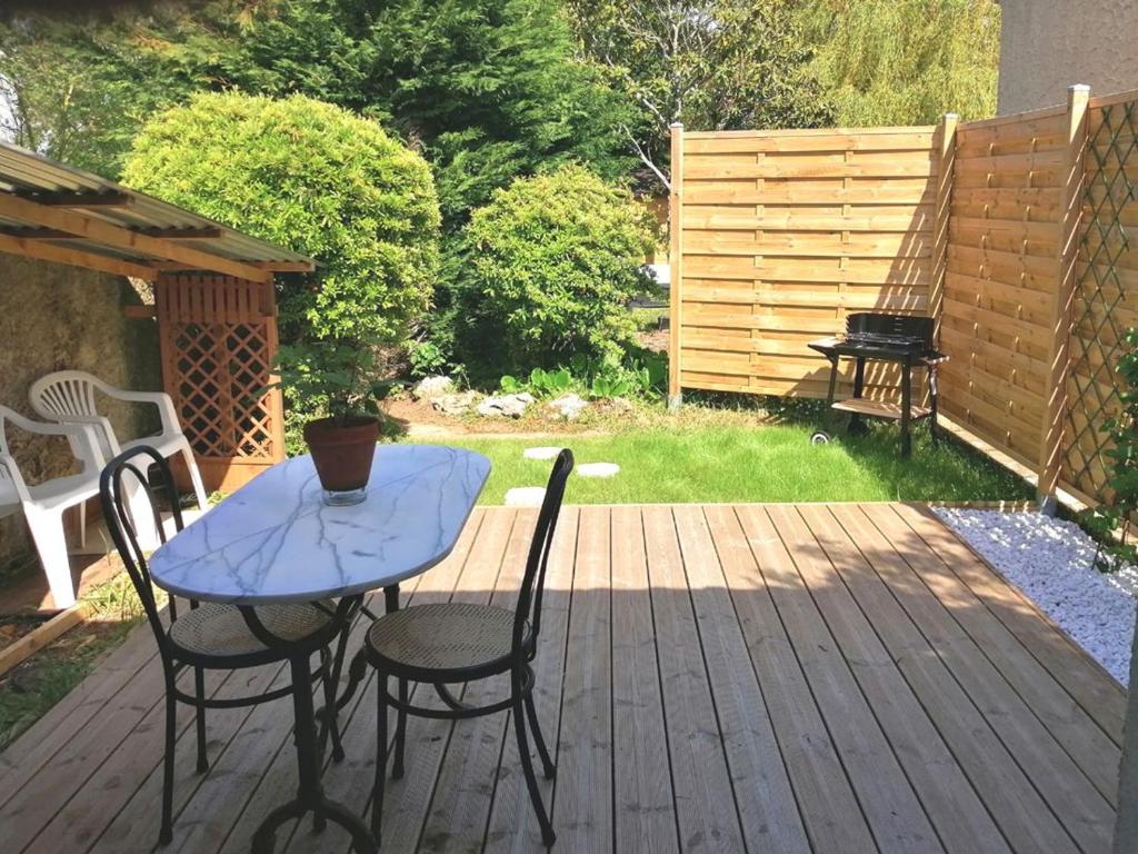 einen Tisch und Stühle auf einer Holzterrasse in der Unterkunft Studio charmant proche centre, terrasse privée, parking, 2km plage - Saint-Jean-de-Monts - FR-1-426-532 in Saint-Jean-de-Monts