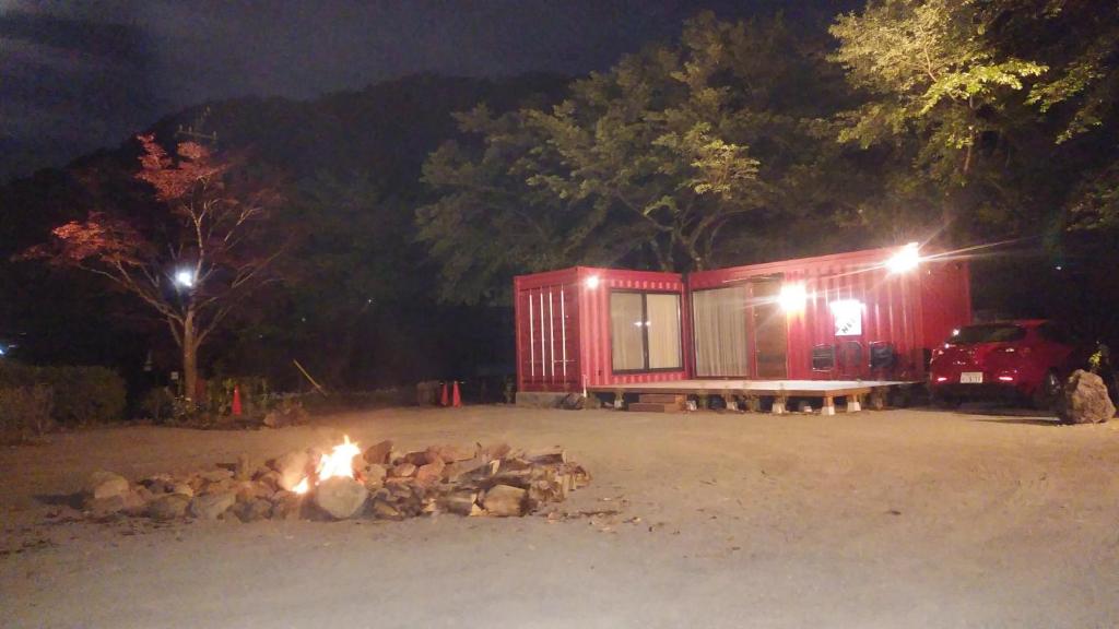 een rood tiny house met een vuurplaats 's nachts bij アイアンネスト in Fujikawaguchiko