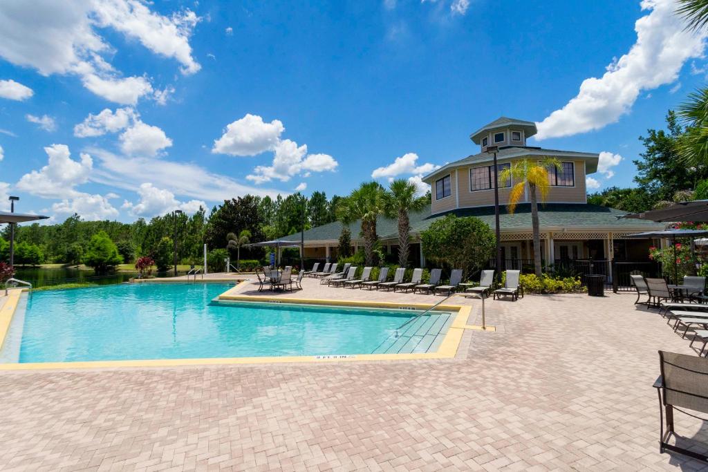a pool at a resort with chairs and a building at Our Happy Place in Kissimmee