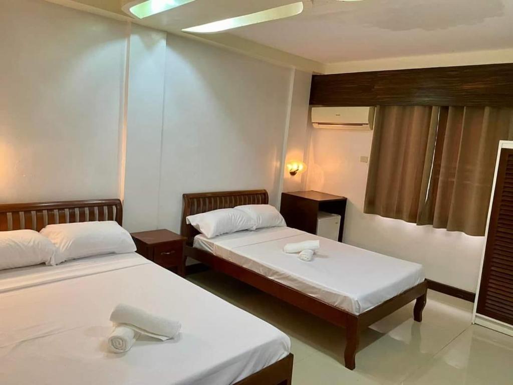 twee bedden in een kamer met twee tafels en twee bedden sidx sidx sidx bij Palawan Rose Garden 1 in Puerto Princesa City