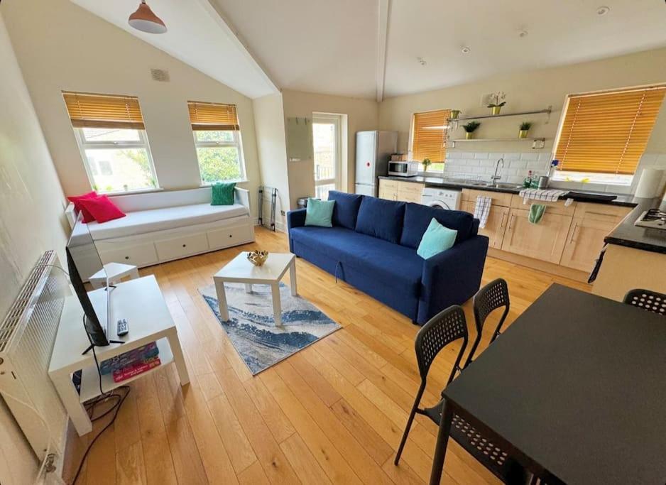 a living room with a blue couch and a kitchen at Lovely 3-bed 20 minutes to Central London in London