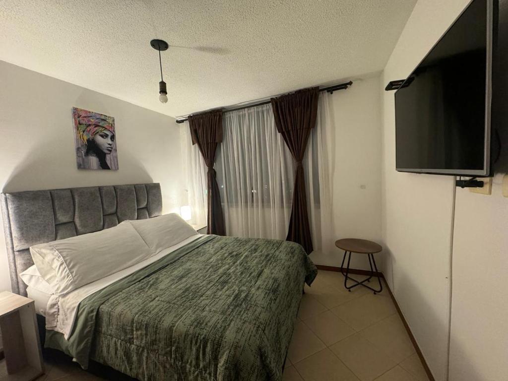 1 dormitorio con 1 cama y TV de pantalla plana en GIBRALTAR, en Manizales