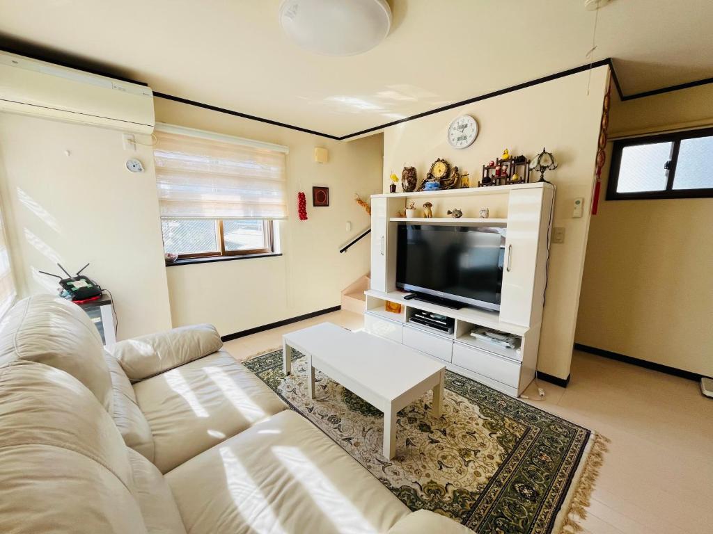Una sala de estar con un sofá blanco y un televisor. en Winter Sale Direct access to each spot Near by Station 9mins to Ikebukuro 10mins to Ueno 13mins to Shinjuku Whole House 3 Bedrooms Max for 8, en Tokio