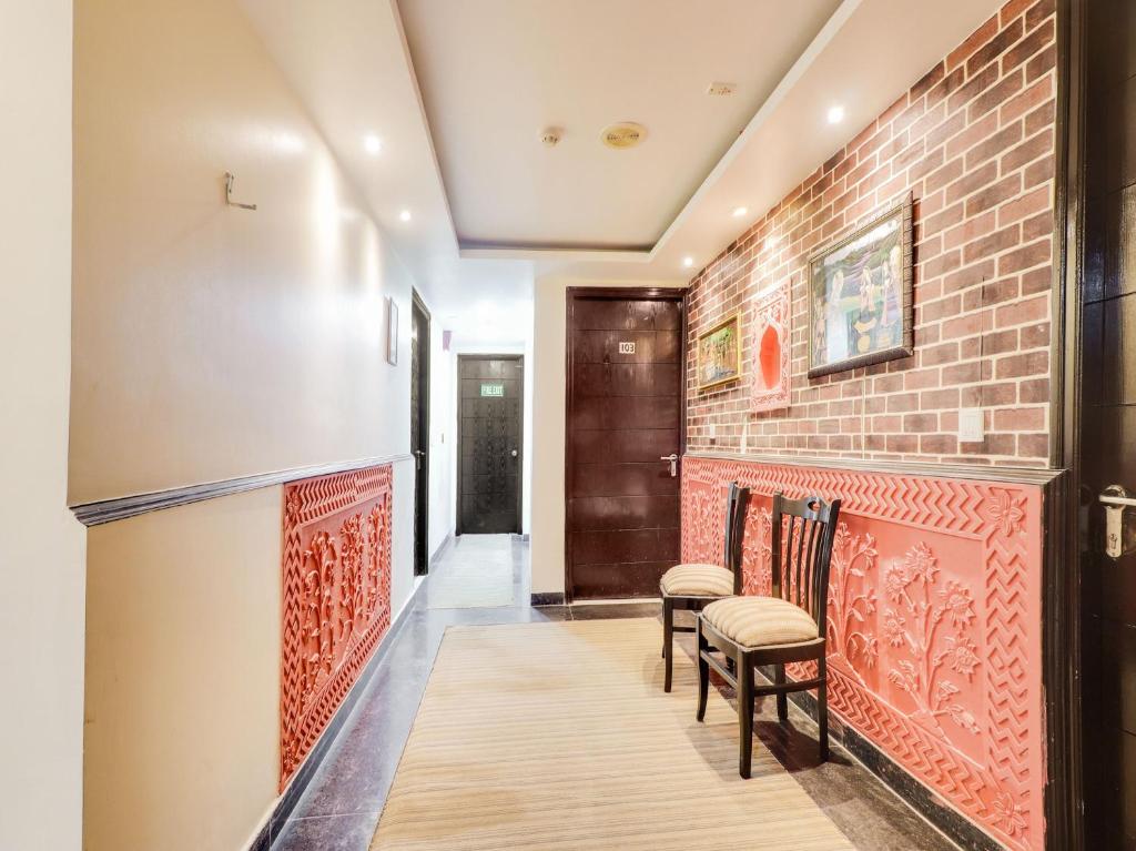 un corridoio con un muro di mattoni e due sgabelli di OYO Flagship HOTEL RUDRA PALACE a Tājganj