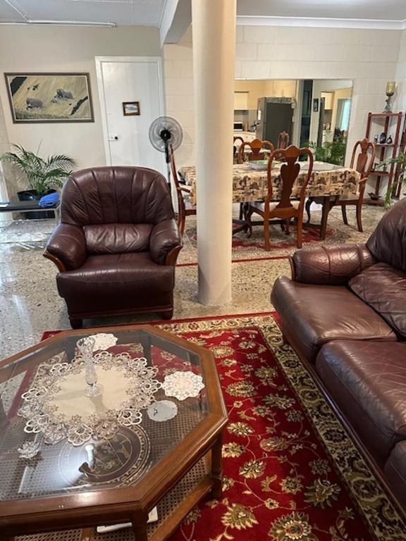 a living room with a leather couch and a table at The singing frogs studio in Coffs Harbour
