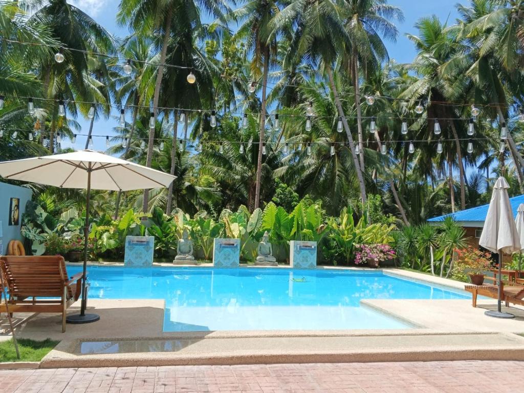 uma piscina com guarda-sol, cadeiras e árvores em House Rental Banaba Tree em Samboan