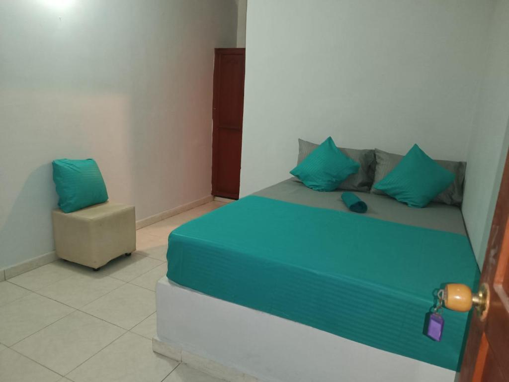 een bed met blauwe kussens en een stoel in een kamer bij Tamarindo in Santa Marta