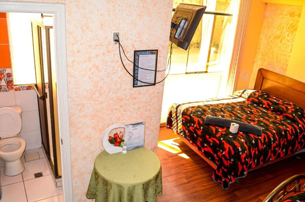 Habitación pequeña con cama, mesa y aseo. en Hotel Lizarraga, en La Paz