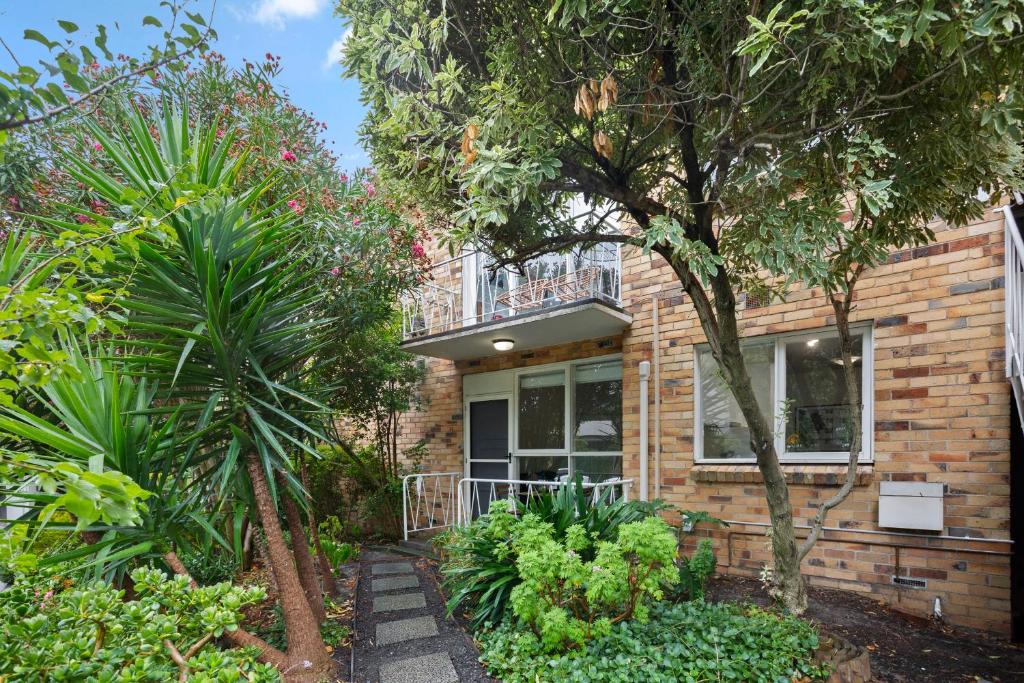 a brick house with a balcony and trees at Complete Host Cromwell Rd Apartments in Melbourne