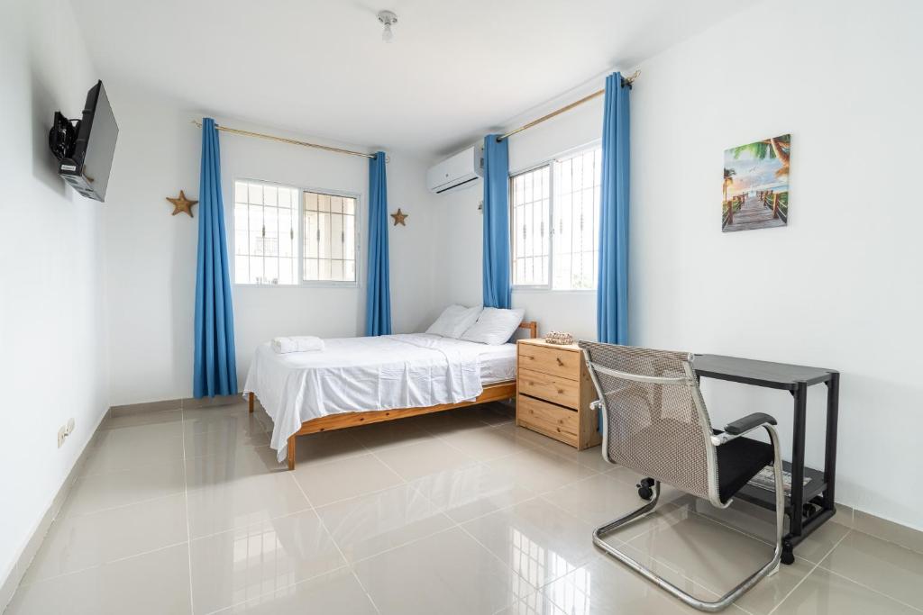 a bedroom with a bed and a desk and windows at Mi refugio cerca del aeropuerto in Santo Domingo