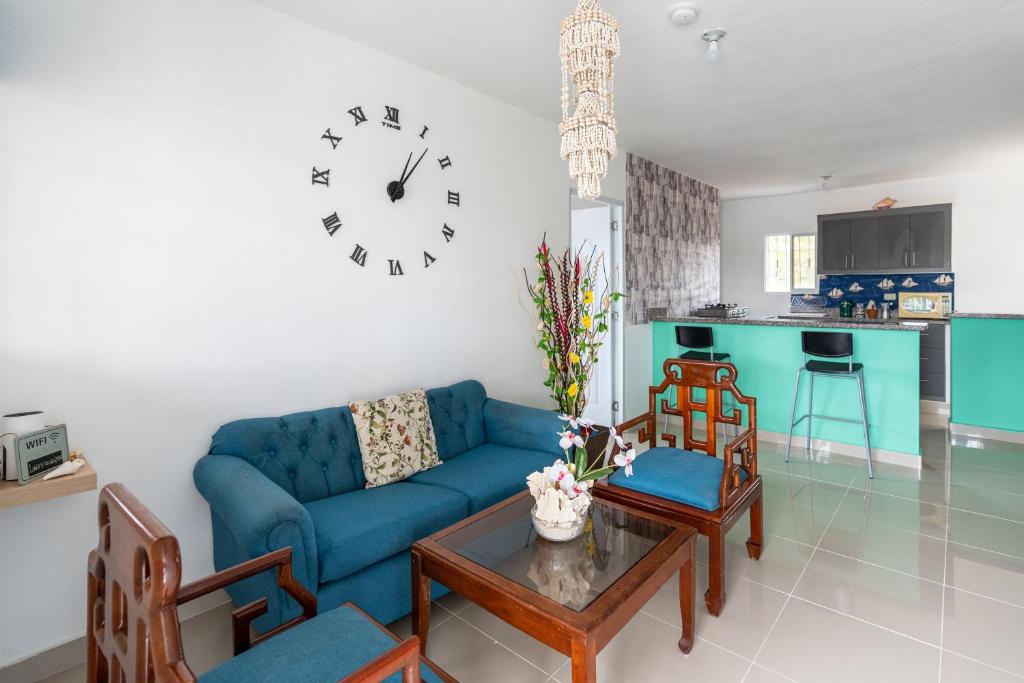 a living room with a blue couch and a clock on the wall at Casa cerca SDQ & Bus Caribe tours in Santo Domingo