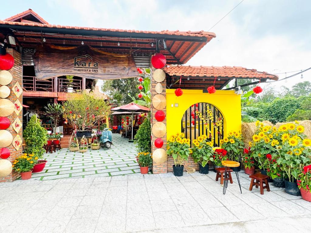 een tuin met een gele poort en bloemen voor een gebouw bij Kara Homestay & Cafe in Can Tho