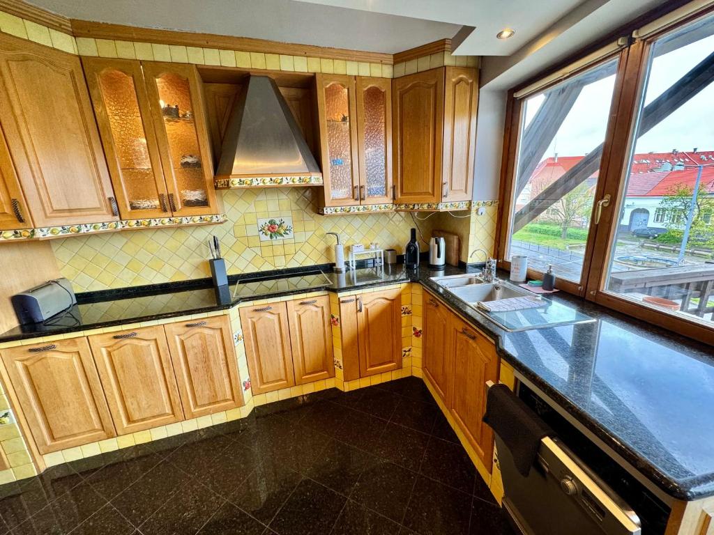 kuchnia z drewnianymi szafkami, umywalką i oknem w obiekcie Bem Apartman w Debreczynie