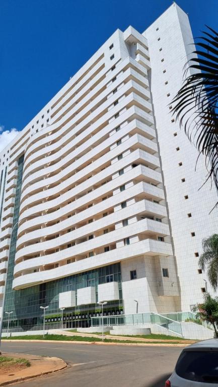 a large white building with a palm tree in front of it at BSB STAY TORRE - FLATS PARTICULARES - SHN in Brasilia
