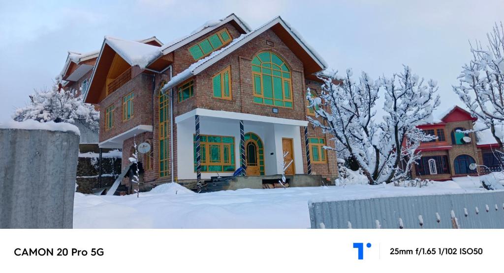 ein Haus mit grünen Fenstern im Schnee in der Unterkunft The Himalayan Inn homestay in Gulmarg