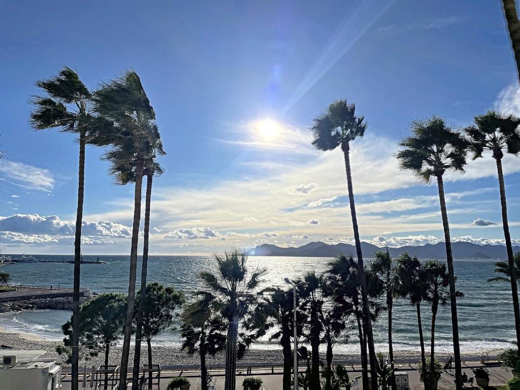 un groupe de palmiers sur une plage avec l'océan dans l'établissement Appartement Cannes, 2 pièces, 4 personnes - FR-1-470-11, à Cannes