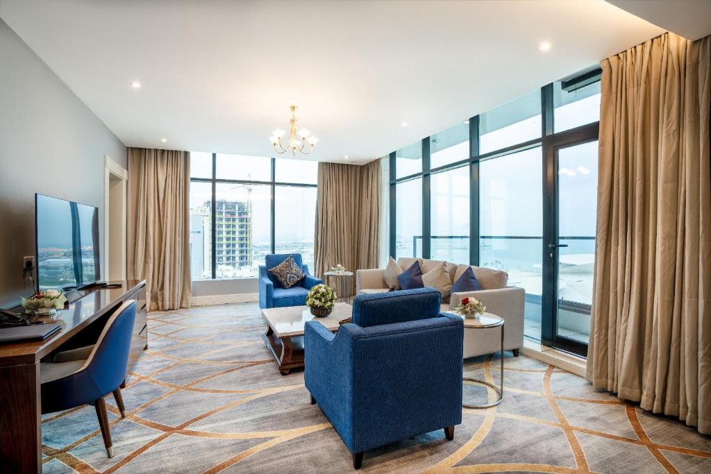 un soggiorno con mobili blu e ampie finestre di فندق شراعوه الملكي - Luxury a Doha