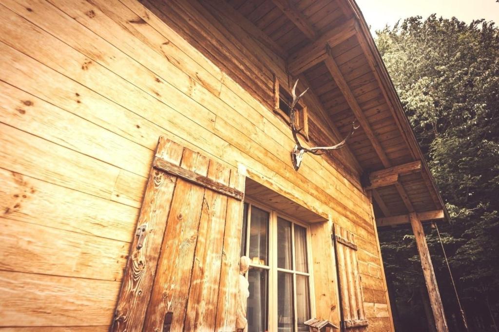 ein Holzgebäude mit einer Tür und einem Fenster in der Unterkunft Stodingerhuette in Koppl