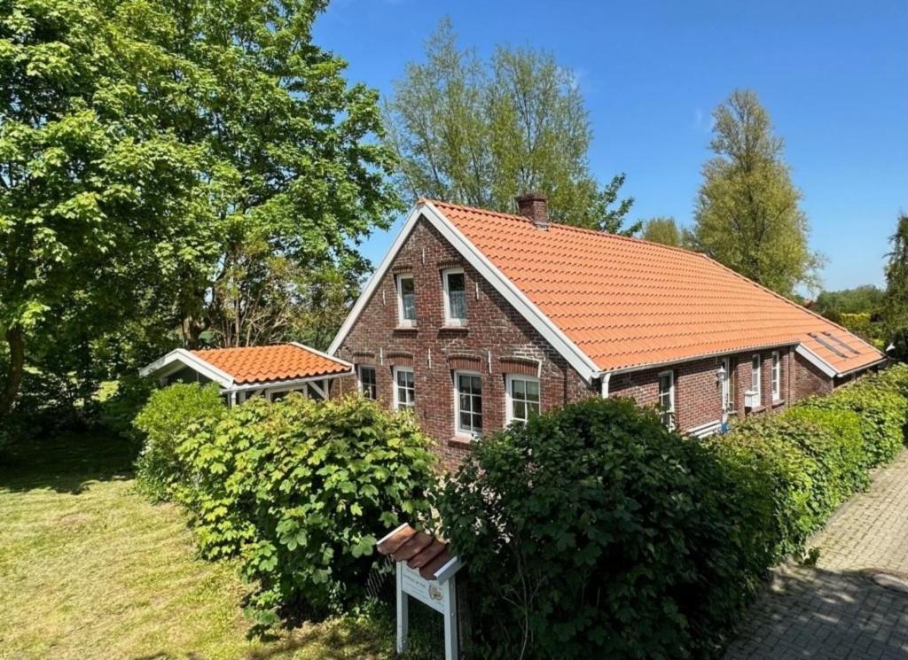 ein altes Backsteinhaus mit orangefarbenem Dach in der Unterkunft Landhaus up Diek in Wittmund