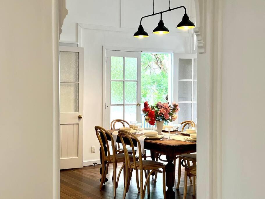 a dining room table with chairs and a vase of flowers at Clementine Cottage in Crows Nest