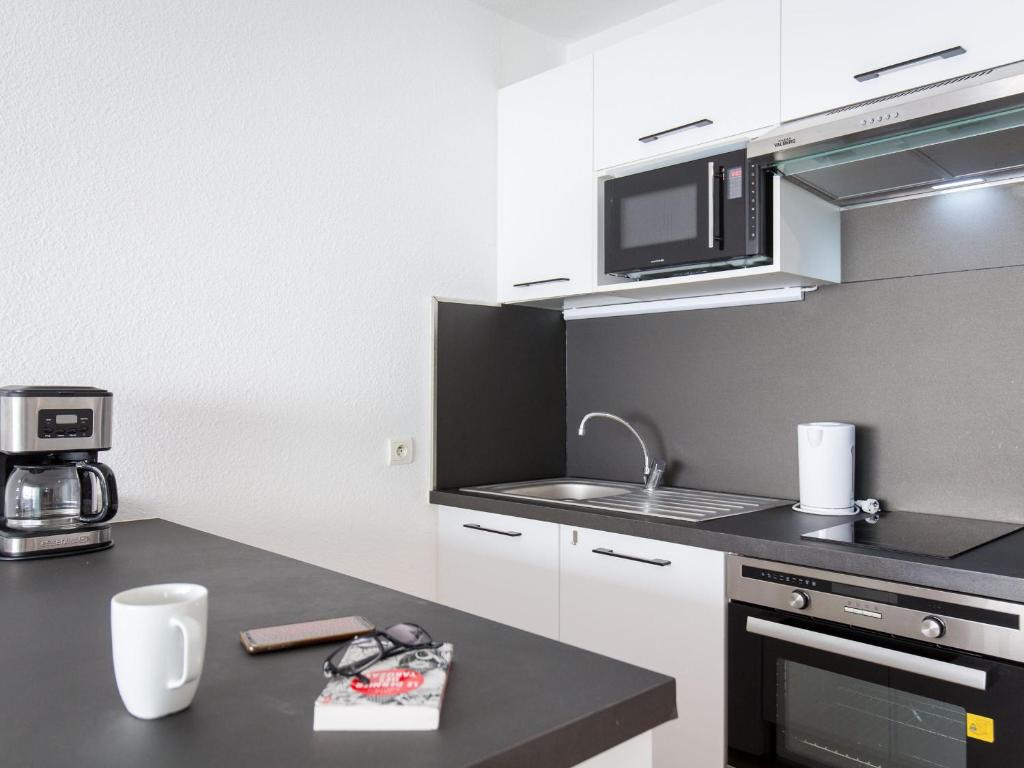 a kitchen with white cabinets and a black counter top at Studio Saint-Raphaël, 1 pièce, 3 personnes - FR-1-466A-42 in Saint-Raphaël