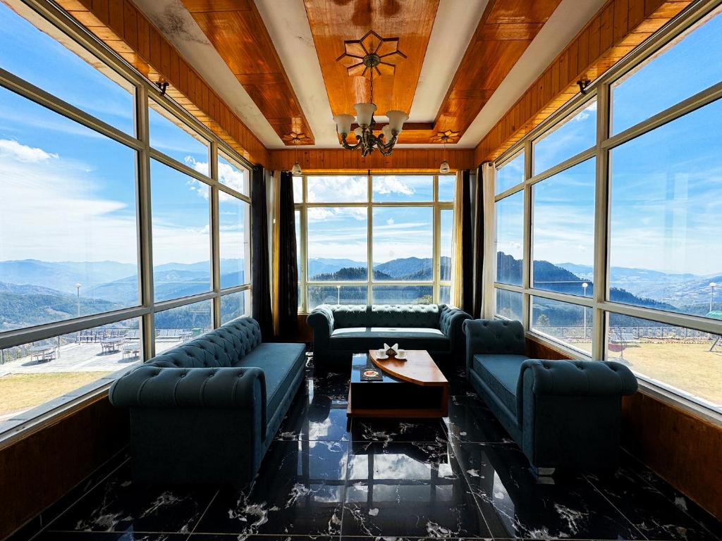Habitación con sofás, mesa y ventanas. en Hawk Eye Resort, en Shimla