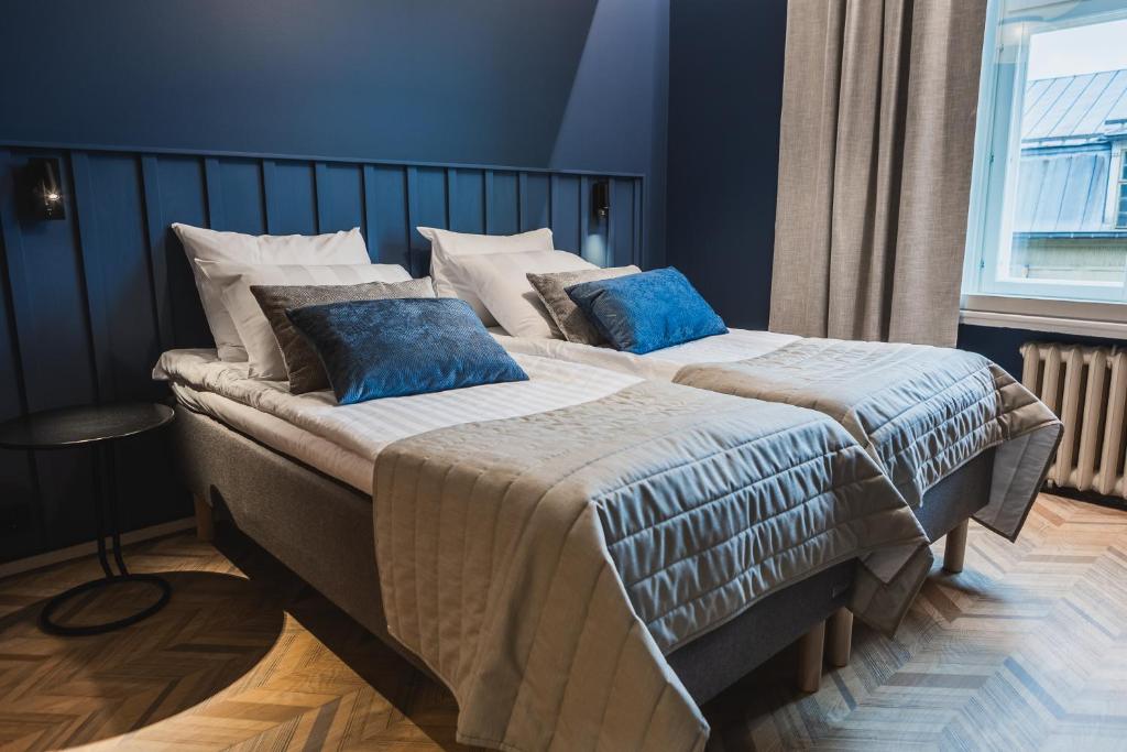 Ineon Hotel في توركو: غرفة نوم بسريرين مع وسائد زرقاء