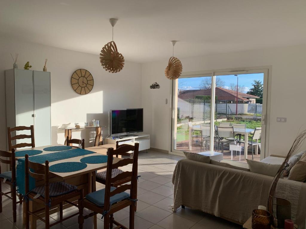 a living room with a table and chairs and a television at Maison 6 pers, climatisée, quartier calme, proche Dune du Pyla et pistes cyclables, ménage inclus - FR-1-319-426 in Parentis-en-Born