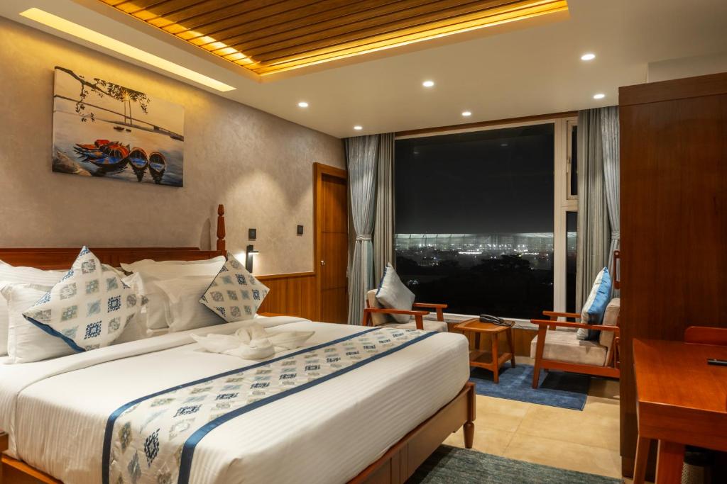 um quarto de hotel com uma cama, uma secretária e uma janela em Ra Vista em kolkata