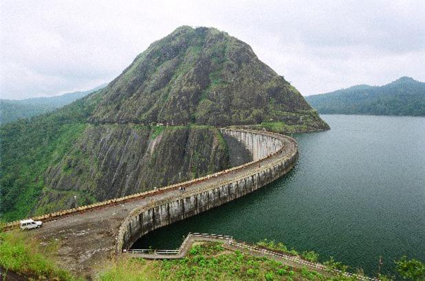 un pont sur une grande étendue d'eau à côté d'une montagne dans l'établissement THE ARK, à Idukki