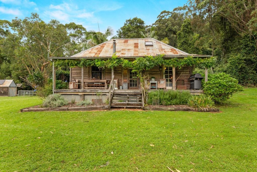 an old house with a rusty roof in a field at Restdown Kangaroo Valley in Barrengarry