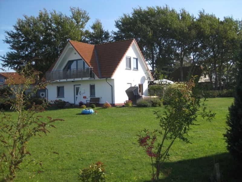 ein weißes Haus mit einem großen Garten mit grünem Gras in der Unterkunft Haus am Bodden in Fuhlendorf