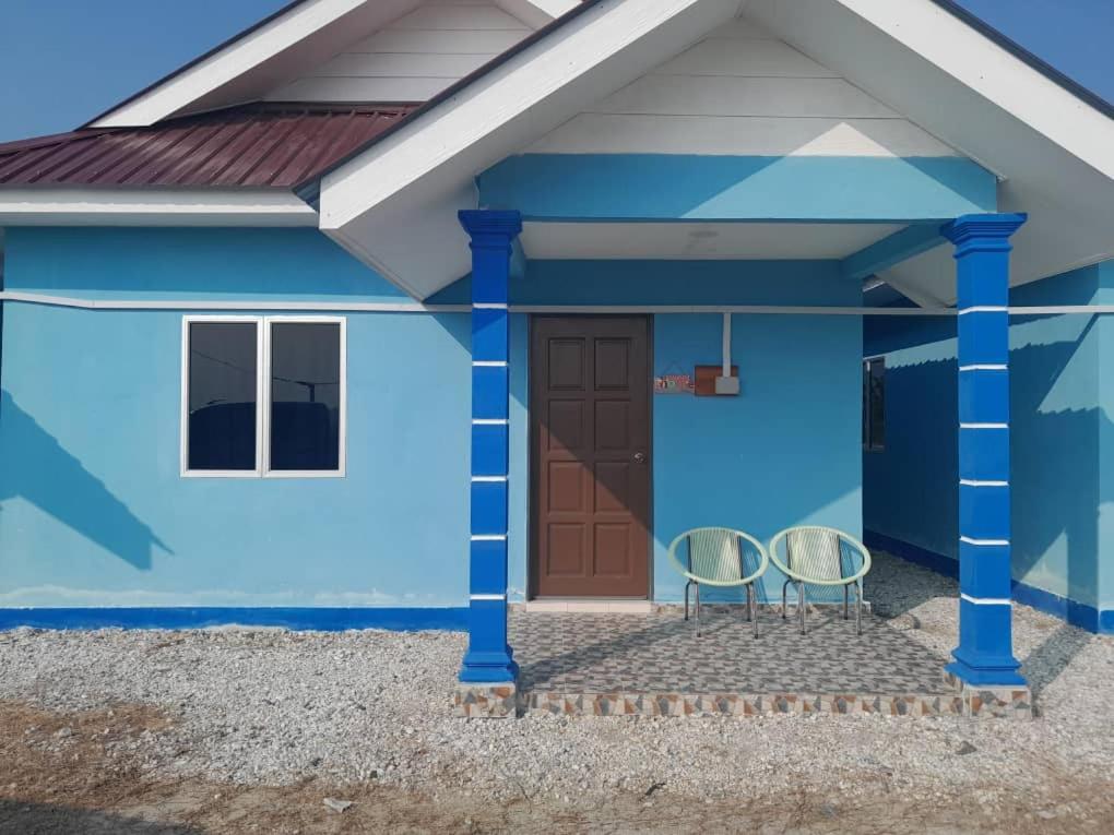 une maison bleue avec deux chaises devant elle dans l'établissement Panorama Indah Homestay, à Sungai Besar