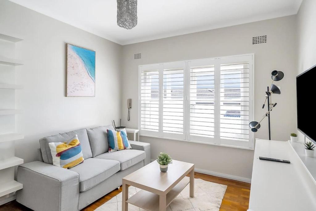 ein weißes Wohnzimmer mit einem Sofa und einem Tisch in der Unterkunft Hall St - Hideaway in the Heart of Bondi Beach in Sydney