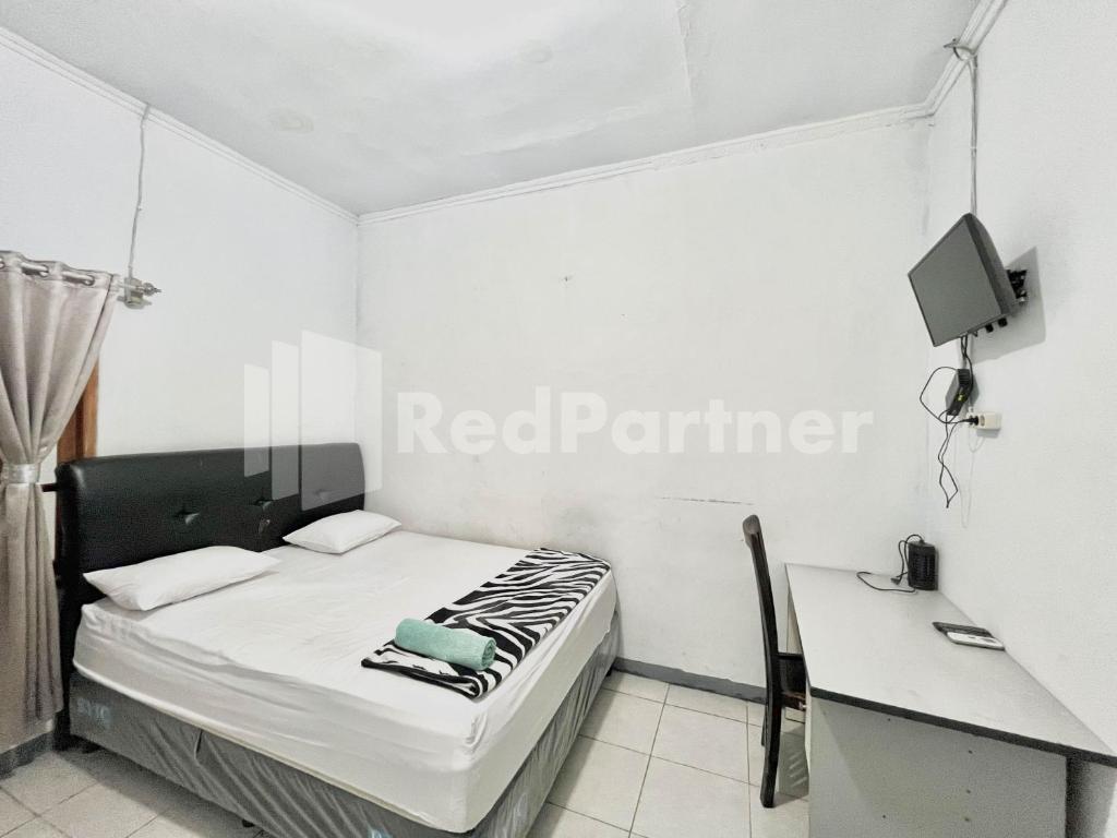 a bedroom with a bed and a desk and a tv at Lafa Park Syariah Mitra RedDoorz in Glonggong