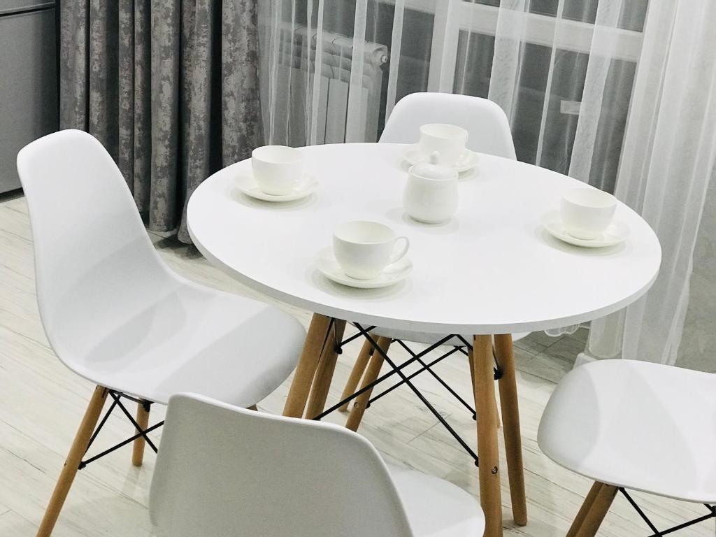 a white table and chairs with cups and saucers on it at Квартира Достар in Karagandy