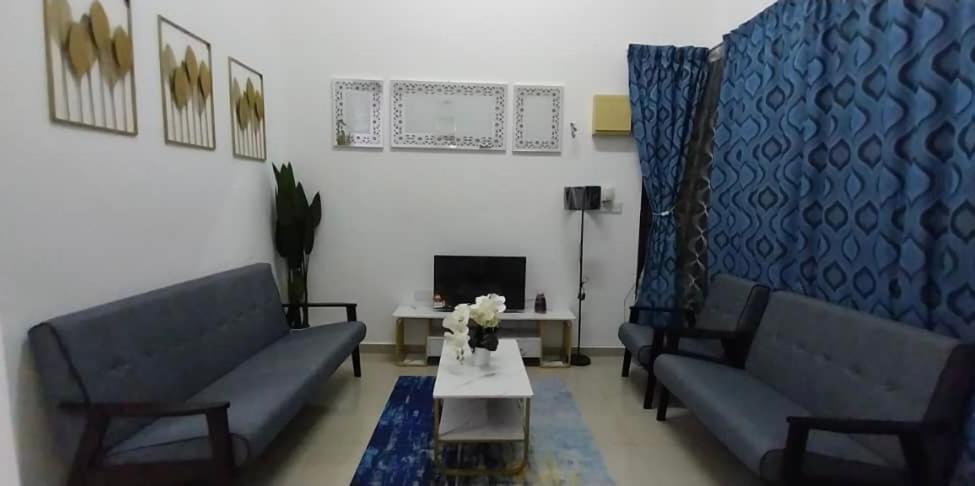 una sala de estar con 2 sofás azules y una mesa. en Orkid Kluang Homestay, en Keluang