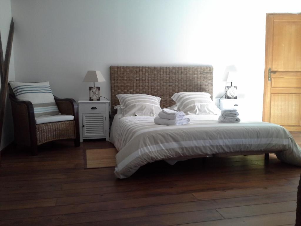 a bedroom with a large bed and a chair at Maison d'hôtes Brameloup Jardin Ovale in Coudures