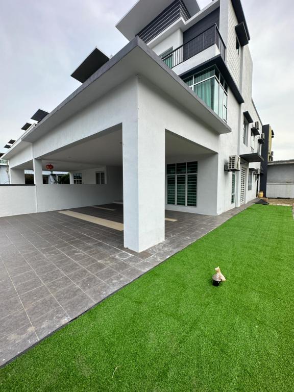 une maison avec une pelouse verte devant elle dans l'établissement Homestay, à Sitiawan