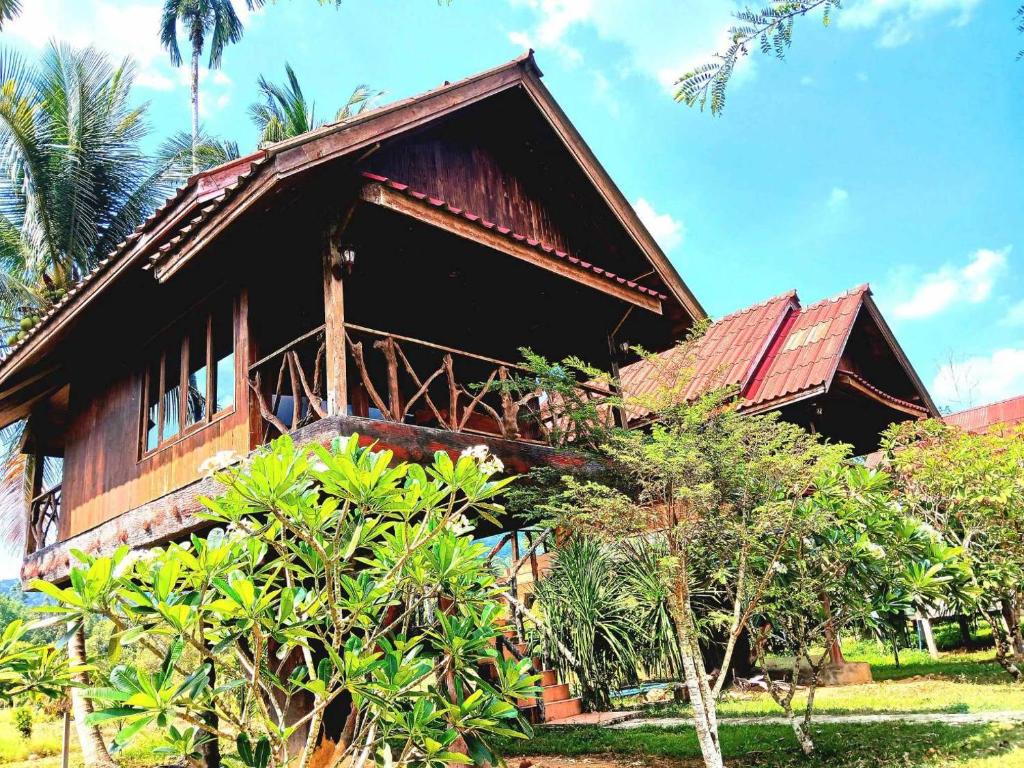 una casa con un tetto rosso e alcuni alberi di Bamboo House a Parco Nazionale di Khao Sok