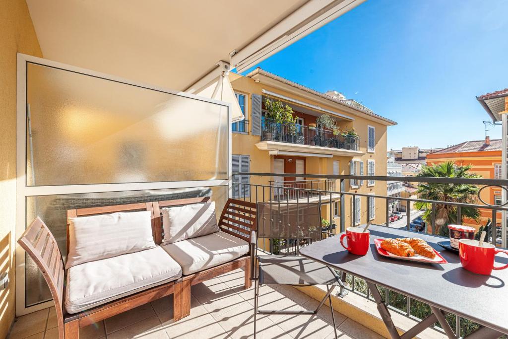 - un balcon avec un canapé et une table avec de la nourriture dans l'établissement Royal Sunny Apt 200m From Beach - Happy Rentals, à Menton