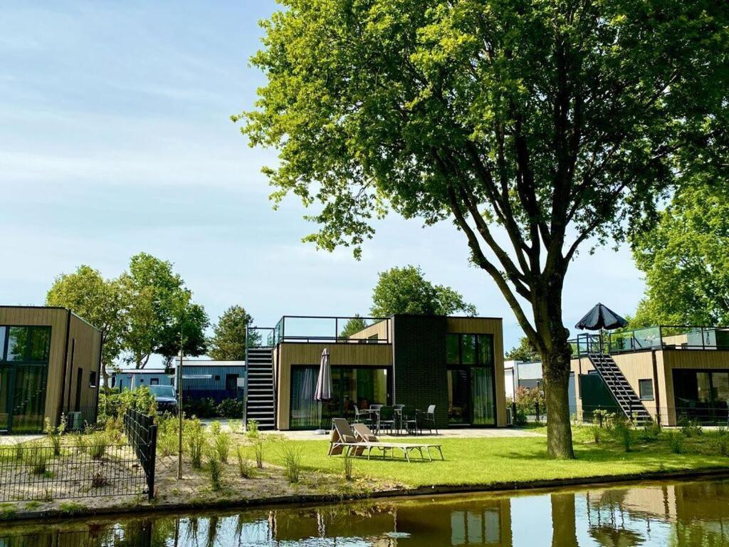 uma casa com uma árvore ao lado de um corpo de água em Cube Elite Noteboom 11 em Hulshorst