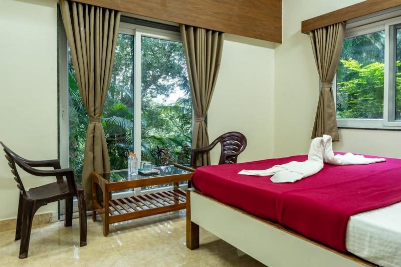 1 dormitorio con cama, mesa y ventana en White Water Resort dandeli, en Dandeli