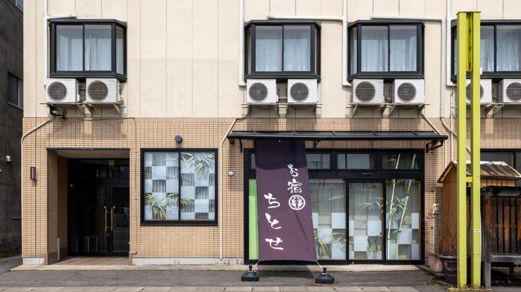 a building with windows and a banner in front of it at Tabist Oyado Chitose in Kazuno