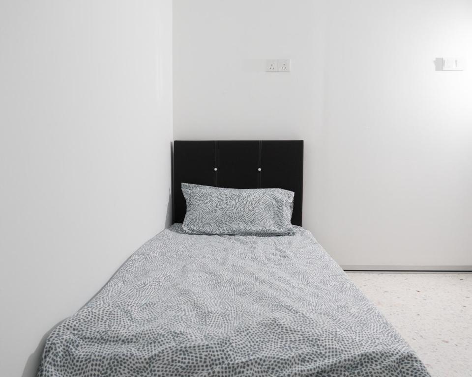 a bed with a gray blanket and a black headboard at Miami Beach Hotel in Batu Ferringhi