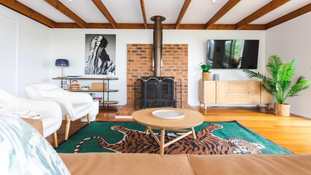 a living room with a fireplace and a table at Nantucket Cottage in Flinders in Flinders