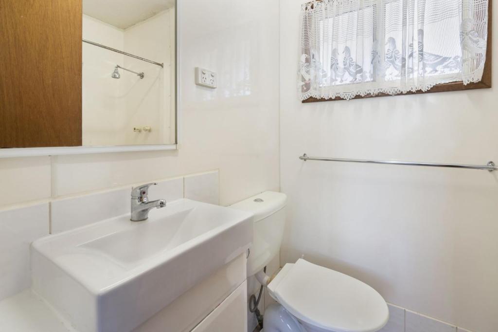 La salle de bains blanche est pourvue d'un lavabo et de toilettes. dans l'établissement Coachstop Caravan Park, à Maitland